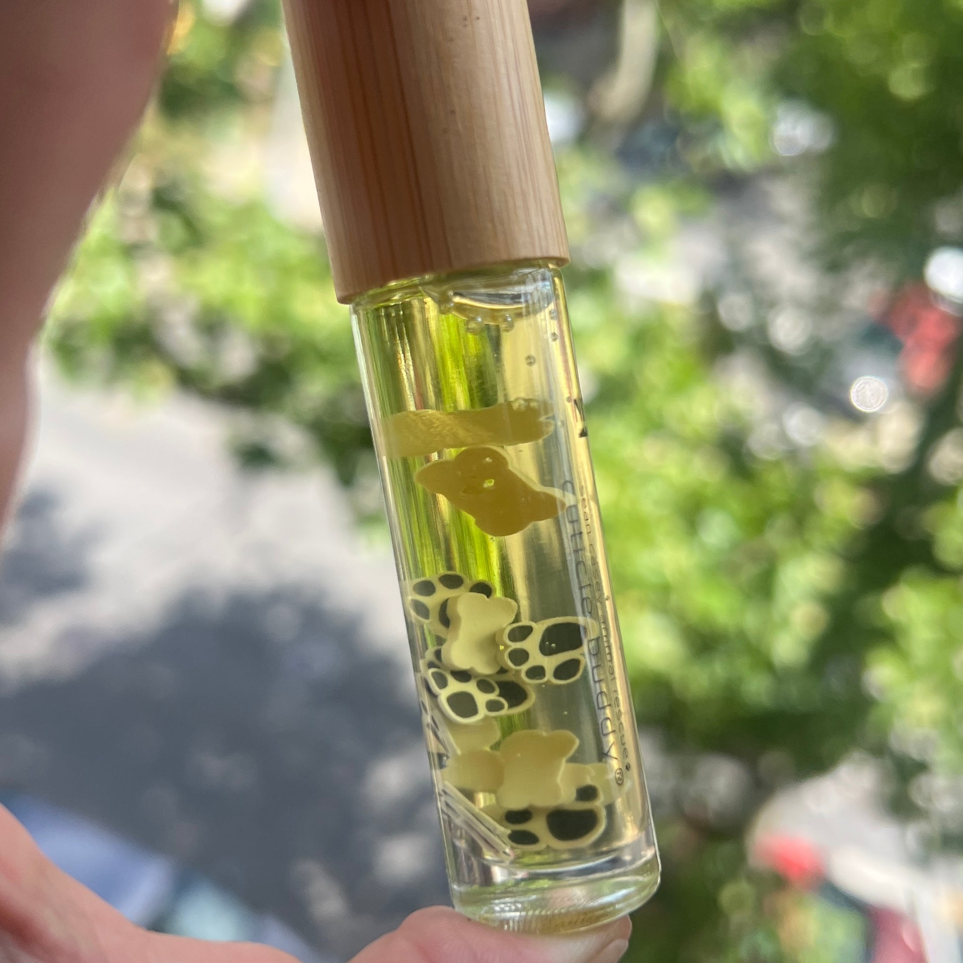 black and white paw print and bone fimo clay slices floating around in a clear bottle of cuticle oil