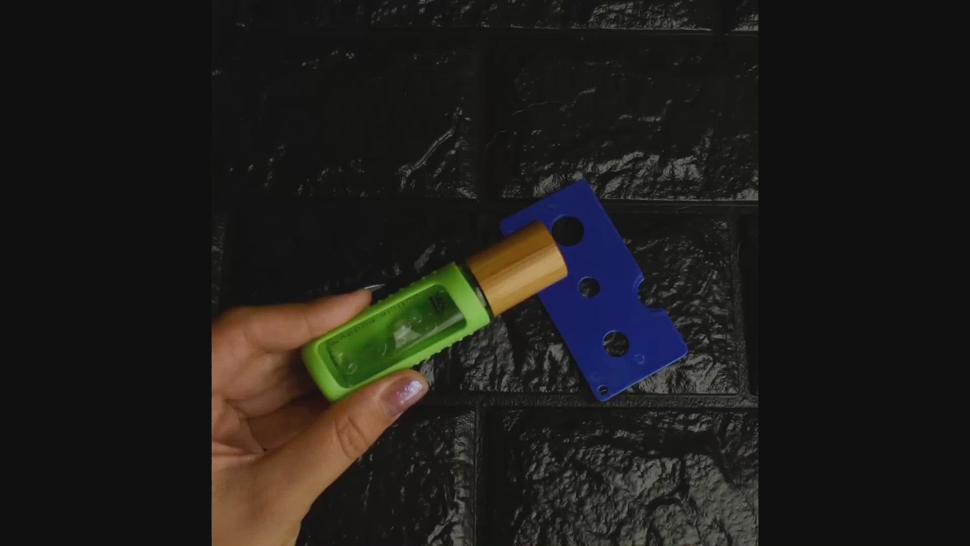 a video showing a pair of hands using a rollerball removal tool to refill a cuticle buddy by working the rollerball out and then pushing it back in with the tool