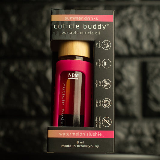 pink rollerball bottle in a hot pink silicone cover with gold aluminum cap labeled cuticle buddy watermelon slushie in it's box on a dark textured background