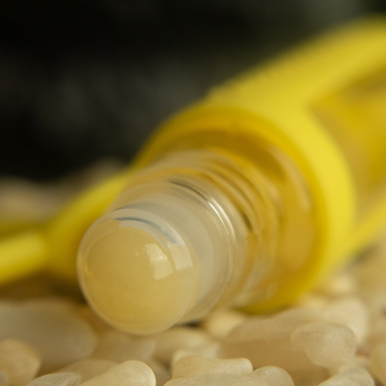 yellow jade rollerball closeup in a pile of rose aurora marble stones
