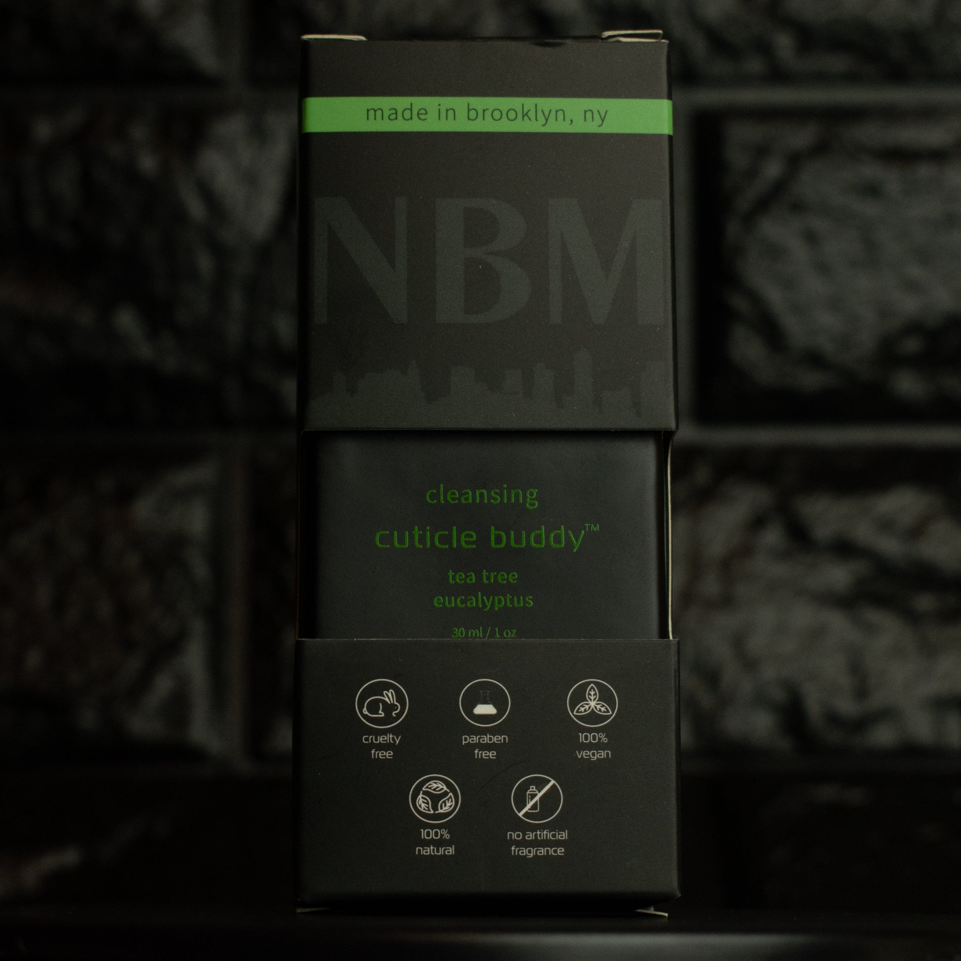 matte Black bottle with wooden dropper labeled cleansing cuticle buddy tea tree eucalyptus 30ml/1oz in its packaging box, on  a dark background