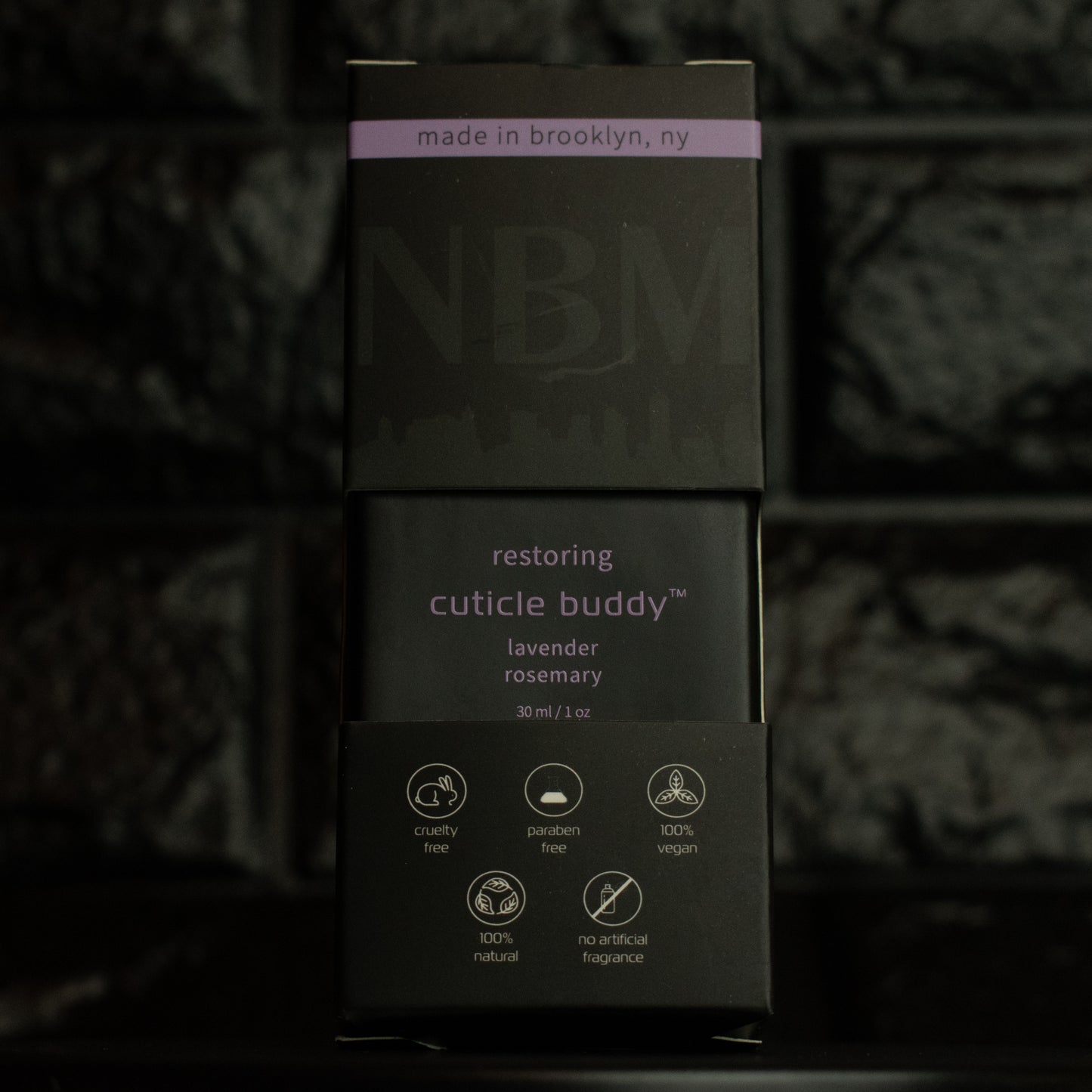 matte Black bottle with wooden dropper labeled restoring cuticle buddy lavender rosemary 30ml/1oz in its packaging box on a dark background