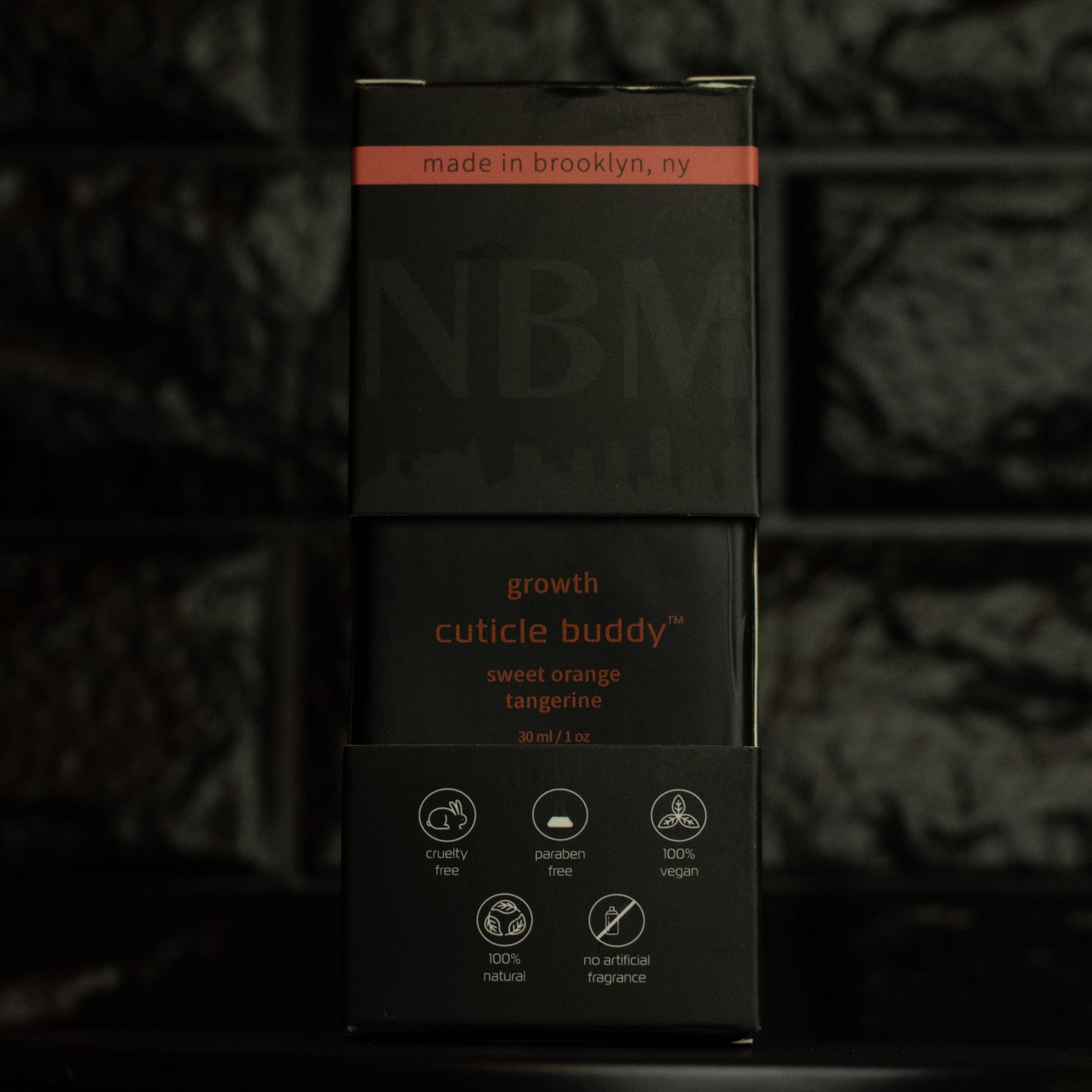 matte Black bottle with wooden dropper labeled growth cuticle buddy sweet orange tangerine 30ml/1oz in its packaging box, on a dark background