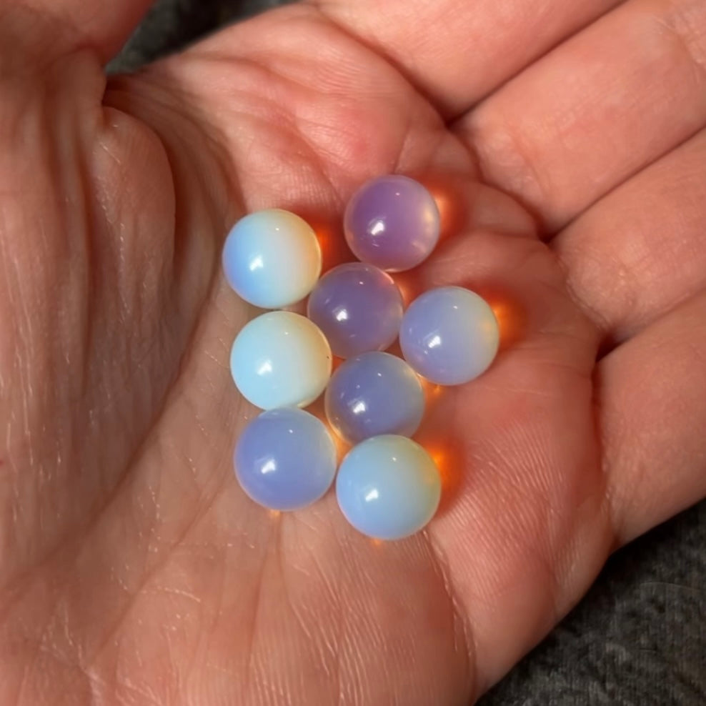 an assortment of opalite rollerballs in a pale hand