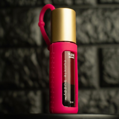 pink rollerball bottle in a hot pink silicone cover with gold aluminum cap labeled cuticle buddy on a dark textured background