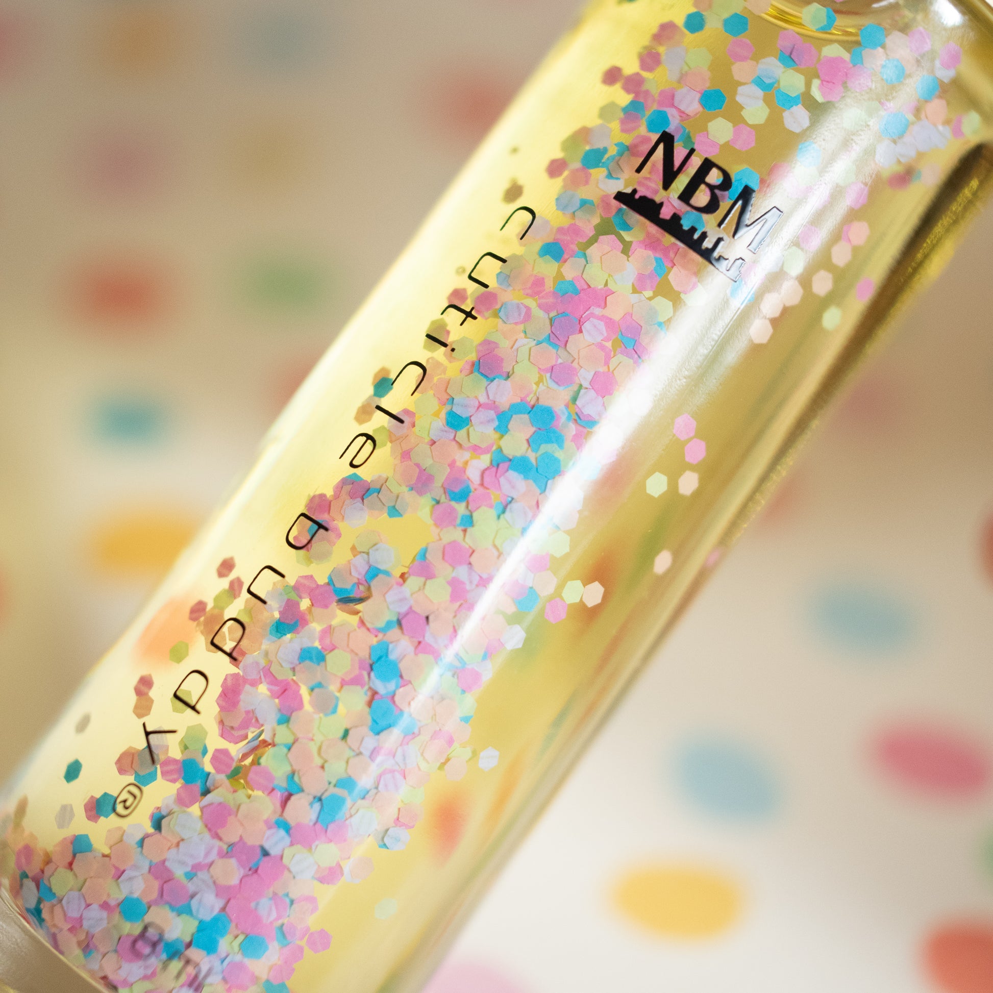 close up shot of a glass bottle of cuticle oil with colorful biodegradable glitter floating inside