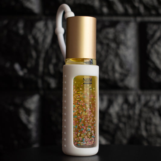 glass bottle of cuticle oil with a gold aluminum cap in a white silicone keychain holder and colorful biodegradable glitter glowing inside
