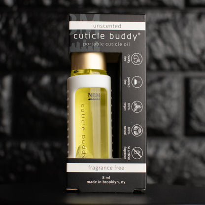 a glass bottle of oil with a gold aluminum cap in a white silicone holder on a black brick background. inside the bottle are clear quartz stones. in its packaging box