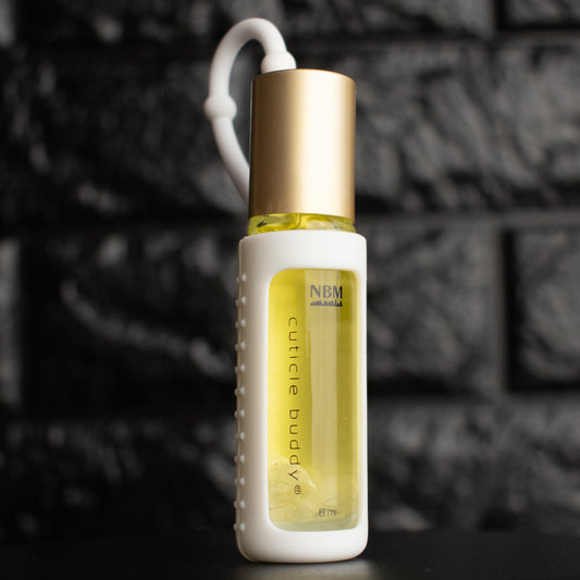 a glass bottle of oil with a gold aluminum cap in a white silicone holder on a black brick background. inside the bottle are clear quartz stones