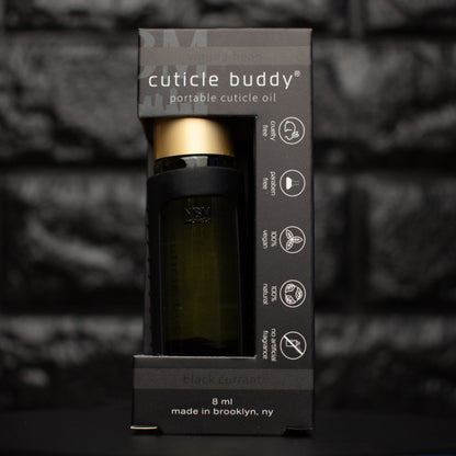 bottle of cuticle oil with gold cap in a black silicone holder in its packaging box