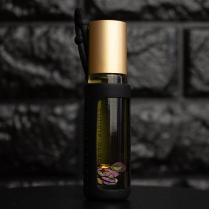 Small glass bottle with gold cap and black label against a dark textured background