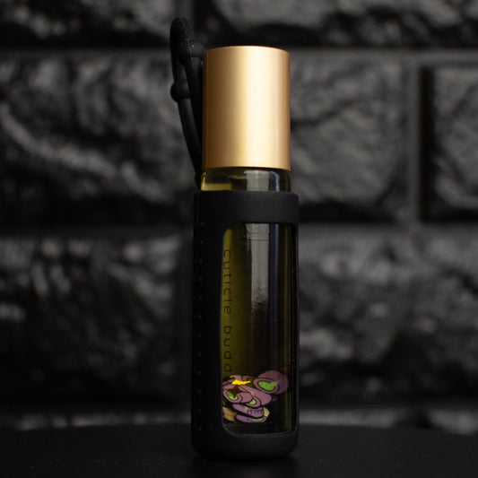Small glass bottle with gold cap and black label against a dark textured background