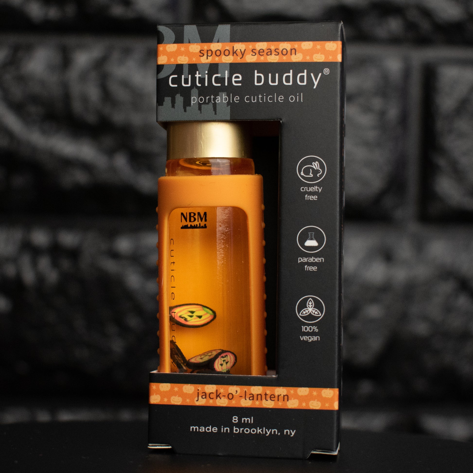 Cuticle oil bottle with packaging labeled 'Cuticle Buddy' on a dark background