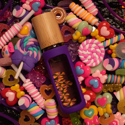 8 ml bottle of cuticle buddy with purple silicone holder and candy fimo clay slices floating inside nestled in a bed of different types of candy