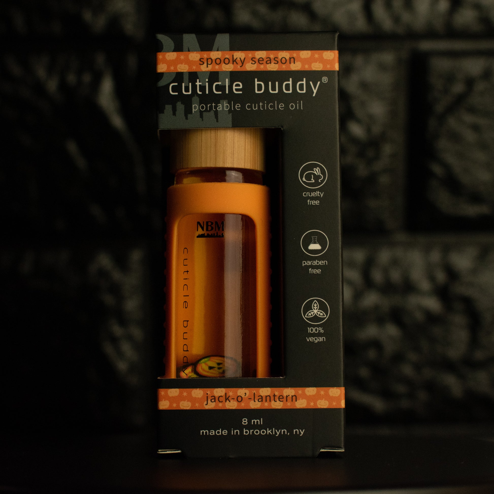 8 ml bottle of cuticle buddy with orange silicone holder and jack-o'-lantern fimo clay slices floating inside in it's box