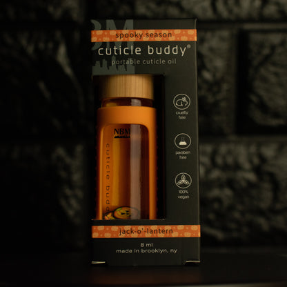 8 ml bottle of cuticle buddy with orange silicone holder and jack-o'-lantern fimo clay slices floating inside in it's box