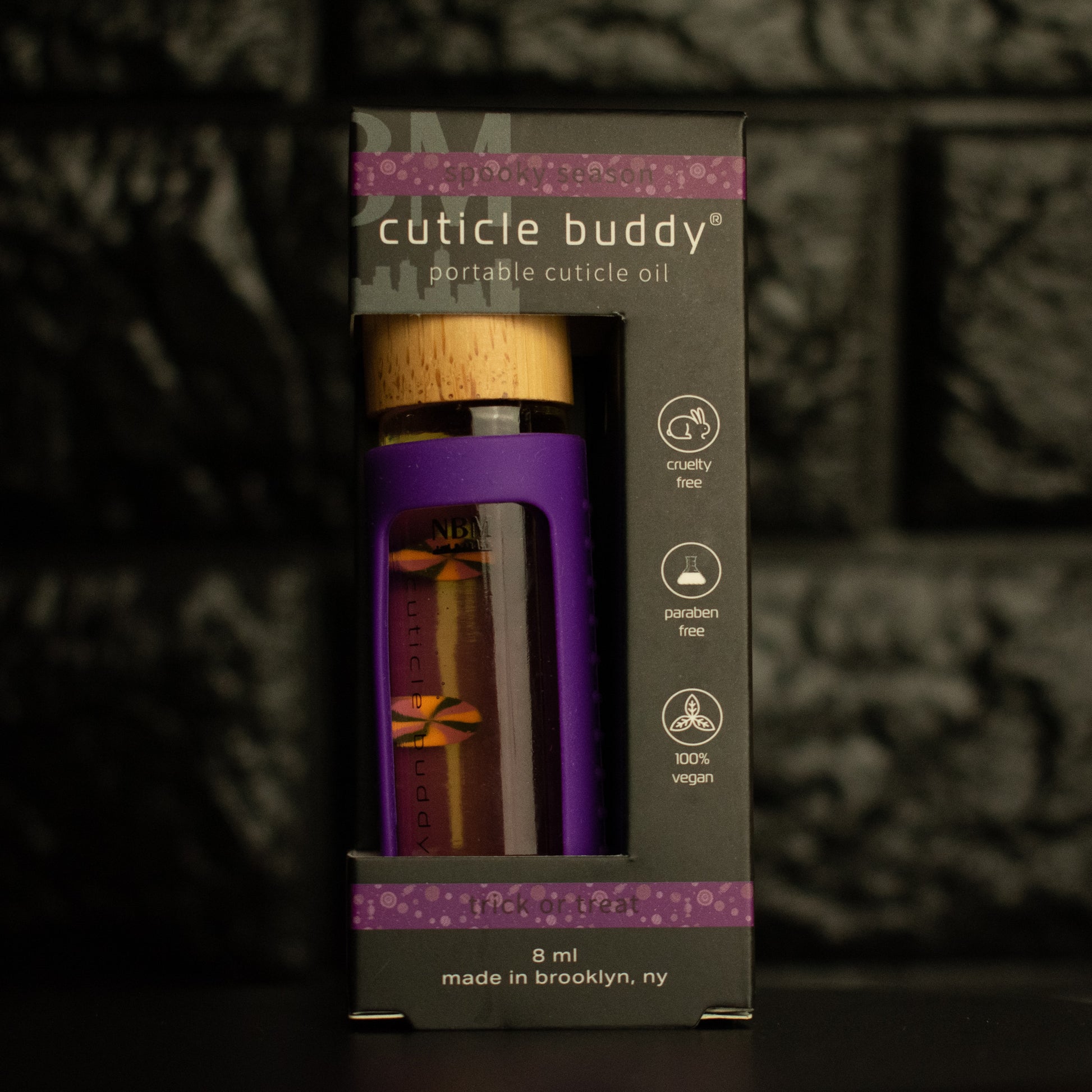 8 ml bottle of cuticle buddy with purple silicone holder and candy fimo clay slices floating inside in its box