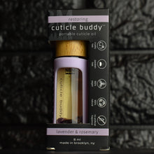 Load image into Gallery viewer, cuticle buddy™ restoring portable cuticle oil inside of it&#39;s packaging box in front of black brick
