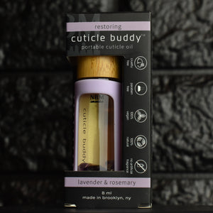 cuticle buddy™ restoring portable cuticle oil inside of it's packaging box in front of black brick