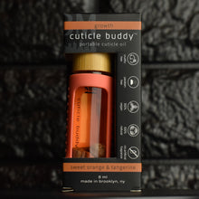 Load image into Gallery viewer, cuticle buddy™ growth portable cuticle oil  inside it&#39;s packaging box in front of black brick
