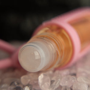 cuticle buddy™ moisturizing portable cuticle oil rose quartz rollerball closeup in a pile of rose quartz stones